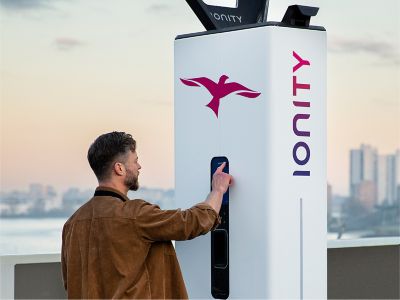 Un homme consultant son appli Hyundai en rechargeant le Hyundai IONIQ 5 à une borne IONITY.