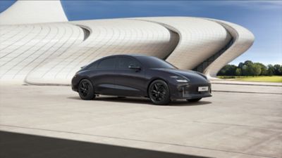 La nouvelle Hyundai IONIQ 6 First Edition 100 % électrique garée devant un bâtiment futuriste.