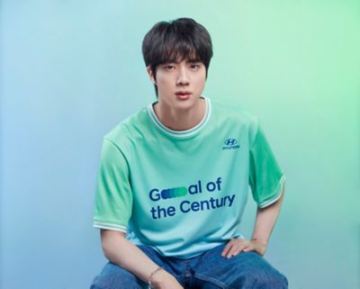 BTS member Jin wearing a  Hyundai Team Century shirt with Goal of the Century on the front.