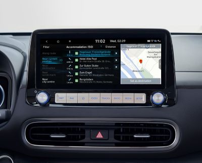 Immagine dello schermo del sistema di navigazione da 10,25” di Nuova Hyundai Kona Electric che mostra punti di interesse in tempo reale.