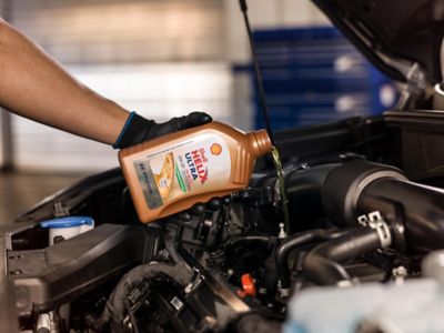 Ekspert serwisowy ASO Hyundai dokonujący wymiany oleju w samochodzie