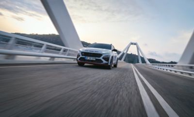 The all-new Hyundai KONA N in the colour Sonic Blue going over a bridge.