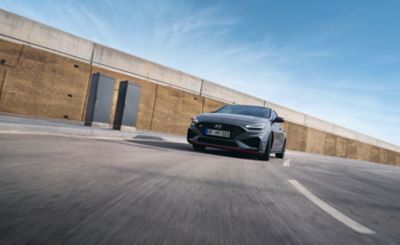 Hyundai Fastback N driving around a corner in an industrial setting.