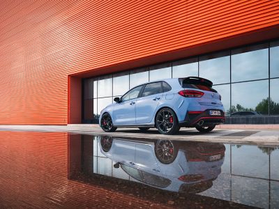 The i30 N performance hatchback from an angle, parked next to a reflective surface.