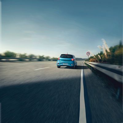 The Hyundai i10 in Aqua Turquoise Metallic driving down a highway.