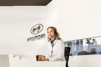 Eine lächelnde Hyundai Mitarbeiterin am Schreibtisch mit Headset.