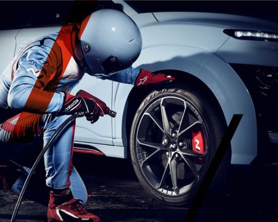 Uomo vestito da pilota controlla la pressione dei pneumatici di modello Hyundai N