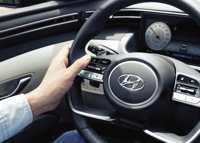 Zbliżenie przycisków na kierownicy w nowym kompaktowym SUV-ie Hyundai TUCSON Hybrid.