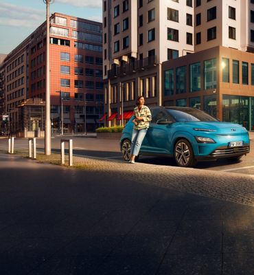 Hyundai KONA Electric parcheggiata con una ragazza accanto