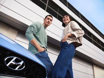 Una giovane coppia appoggiata al cofano della berlina ad alte prestazioni Nuova Hyundai i30 N.