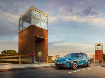 The Hyundai Kona Electric driving over a bridge in the evening. 