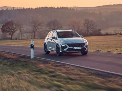 Hyundai KONA N hot SUV conduciendo por una carretera rural al atardecer