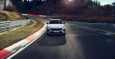 Hyundai KONA N driving on a race track at sunset.