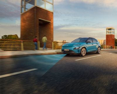 The Hyundai Kona Electric with Forward Collision-Avoidance Assist driving over a bridge. 