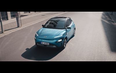 The new Hyundai Kona Electric SUV driving on a city street.