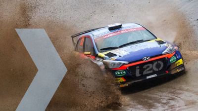 Hyundai Motorsport customer racing rally car i20 R5 in action driving through pudle of mud.