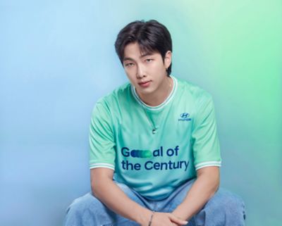 BTS member RM wearing a  Hyundai Team Century shirt with Goal of the Century on the front.