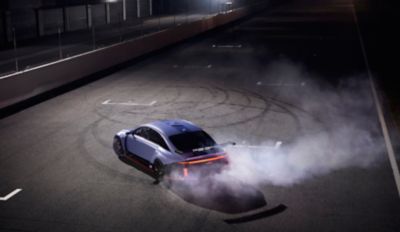 Hyundai RN22e all electric rolling lab doing a doughnut spin on asphalt with smoking tyres.
