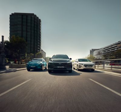 Visual showing the Hyundai  Kona Electric, Nexo and IONIQ Hybrid cars driving down an urban street