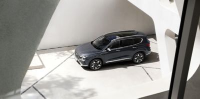 Nowy 7-miejscowy SUV Hyundai SANTA FE Hybrid zaparkowany przed domem – ujęcie z przodu.
