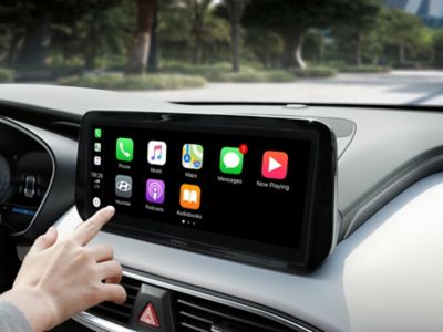 Dotykový displej Hyundai s ikonami Apple Car Play zobrazenými na obrazovce.