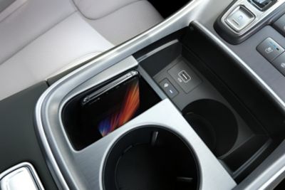 Close-up van het draadloze oplaadvak en de bekerhouders van de Hyundai SANTA FE Plug-in Hybrid.
