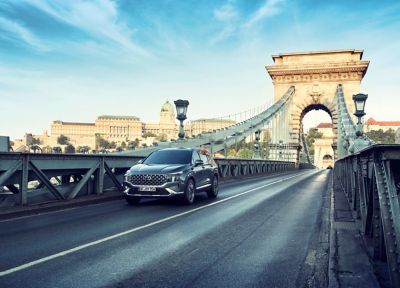 The Hyundai Santa Fe Hybrid 7 seat SUV in grey driving over a bridge.