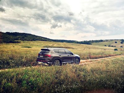 The Hyundai Santa Fe Plug-in Hybrid 7 seat SUV driving over a country lane in the hills.