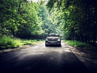 Nowy SUV Hyundai Santa Fe Plug-in Hybrid z siedmioma siedzeniami na leśnej drodze.