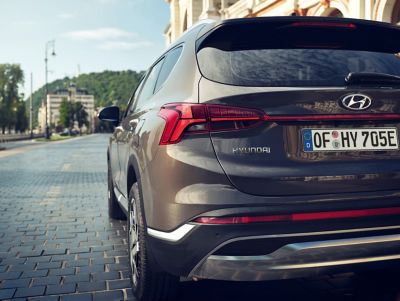 Hyundai Santa Fe Plug-in Hybrid 7 seat SUV from behind driving down a city street.