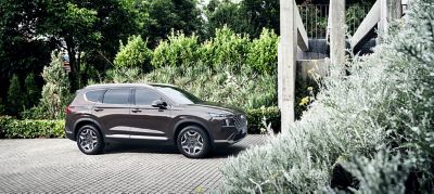 The Hyundai Santa Fe Plug-in Hybrid 7 seat SUV parked in front of a modern house.