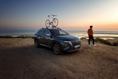 The Hyundai TUCSON with genuine accessories in the sunset at a beach.