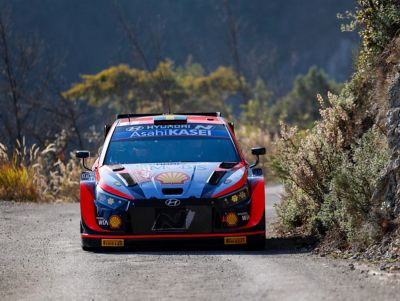 The Hyundai i20 N WRC Rally1 driving on a gravel road.