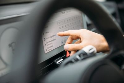 A driver of a Hyundai electric vehicle looking for a charging station on the display.