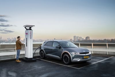 Elektrische IONIQ 5 wordt opgeladen aan IONITY-laadpunt op dak van gebouw.