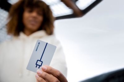 Kobieta trzyma kartę Charge myHyundai do ładowania samochodów elektrycznych.