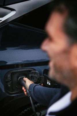 Ein Mann steckt einen Ladestecker in den Ladeanschluss eines Hyundai.
