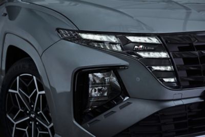 Detaily odznaku N Line a světlometů zcela nového modelu Hyundai TUCSON N Line ve stínu šedé.