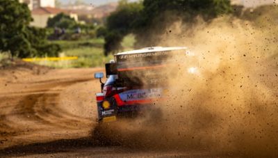 Motorsport driver Dani Sordo's Hyundai i20 drifting on a dirt road.