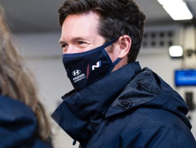 Hyundai Motorsport co-driver Martijn Wydaeghe smiling at crew members with mask.