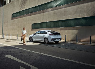 Woman walking away from her Hyundai IONIQ parked on the street.