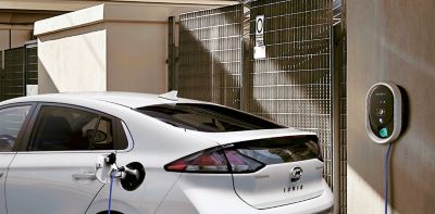 Hyundai IONIQ plugged into a wallbox on an outside wall