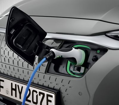 A woman plugging her Hyundai IONIQ 5 electric vehicle to a charging station.