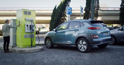 Hyundai KONA Electric standing at a public fast-charging station