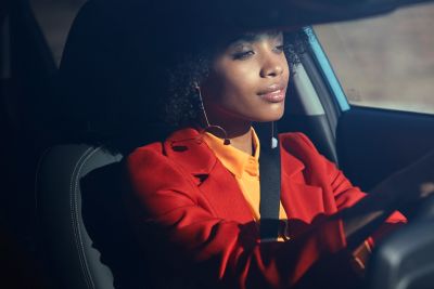 Une femme assise avec le sourire au volant du Hyundai KONA Electric.