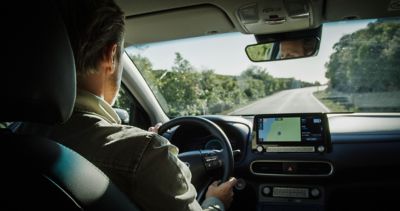 inside a Hyundai KONA electric, driving down a country road