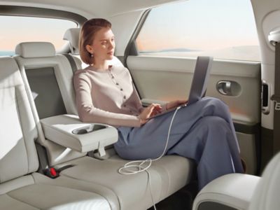 Eine Frau mit Tablet-Computer genießt den Fahrkomfort auf der Rückbank eines geräumigen Hyundai.