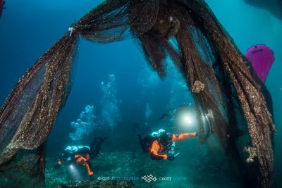 Two volunteers from Ghost Divers recovering discarded fish nets underwater for recycling.