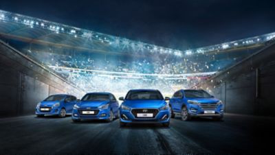 Cztery modele Hyundai stojące przed zatłoczonym stadionem.