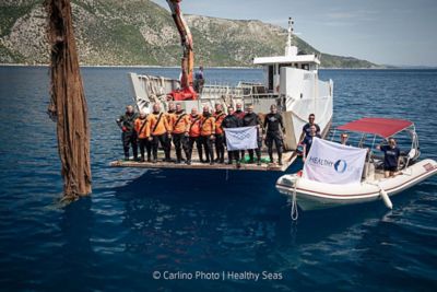 L'ensemble de l'équipage de Healthy Seas, réuni sur deux petits navires dans une baie d'Ithaque, en Grèce, présentant un filet récupéré du fond de l'océan
